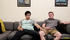curly haired stud plays with his cute friend on a gray couch